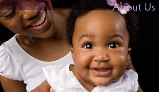 Baby girl smiling directly into the camera while her mother looks over the babies shoulder and smiles at the child. Title text is About Us.